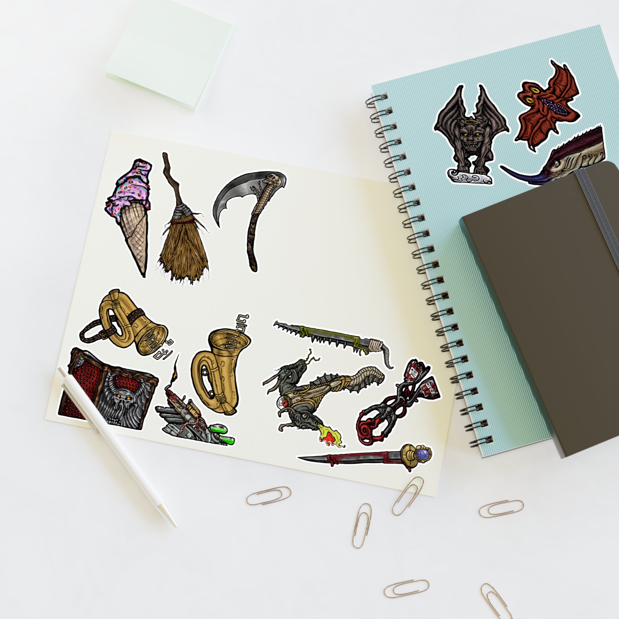 Freaky Features Sticker Sheet Set #4, transparent die-cut sheet with 14 hand-drawn weapons and creatures including ice cream cone, witch broom, skeletal scythe, bat-winged hellbeast, cursed tome and more
