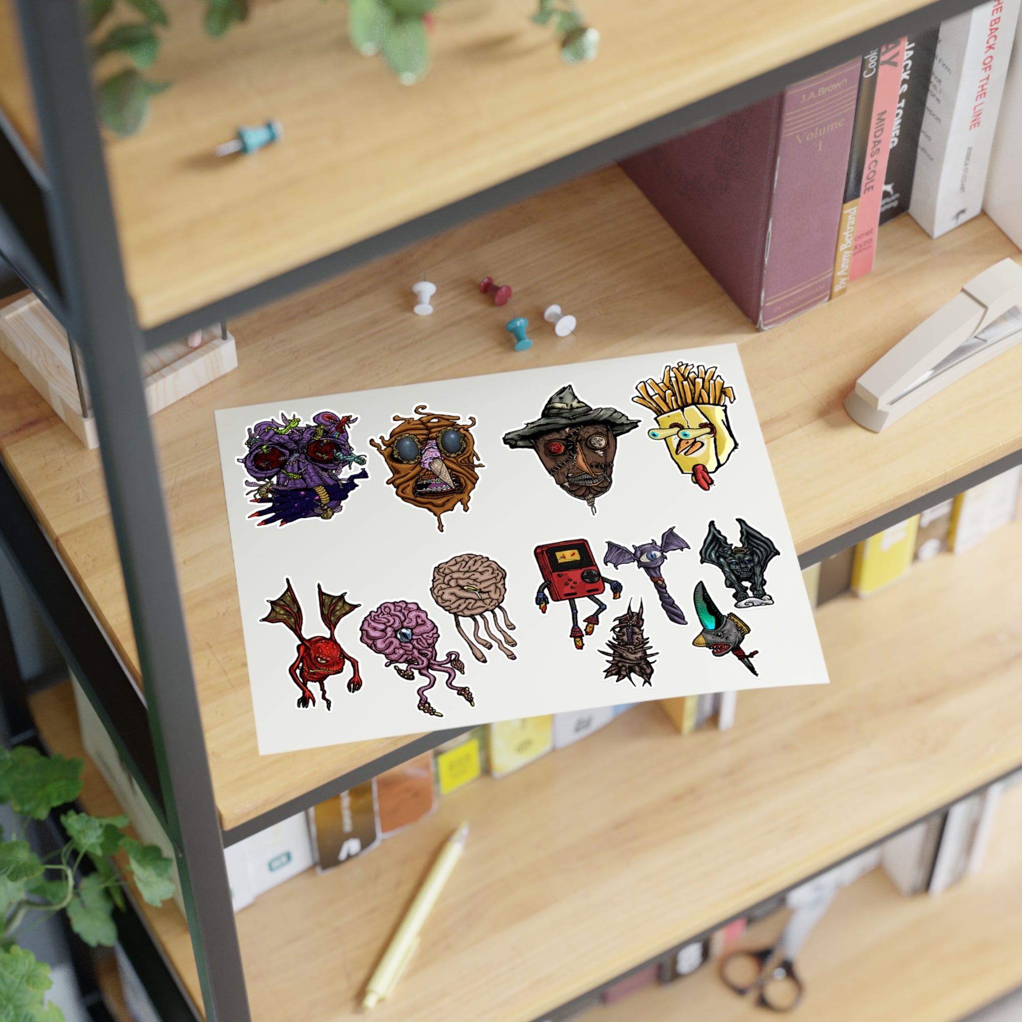 Freaky Features Sticker Sheet Set #3 , transparent die-cut sheet with 12 hand-drawn monsters and creatures including alien swarm, melting chocolate head, scarecrow, french fry box, walking Game Boy ( Gamerpal) , brains, and various weird weapons/creatures
