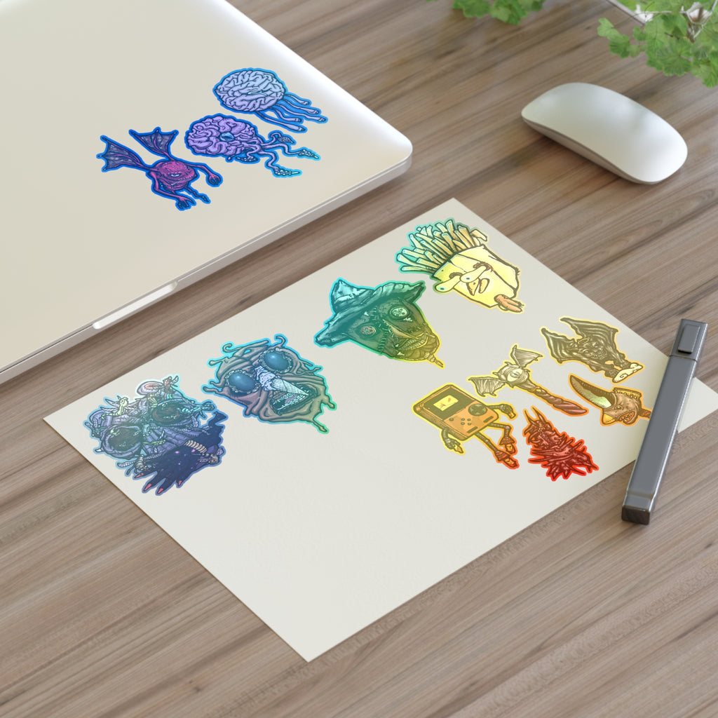 Freaky Features Sticker Sheet Set #3 , transparent die-cut sheet with 12 hand-drawn monsters and creatures including alien swarm, melting chocolate head, scarecrow, french fry box, walking Game Boy ( Gamerpal) , brains, and various weird weapons/creatures
