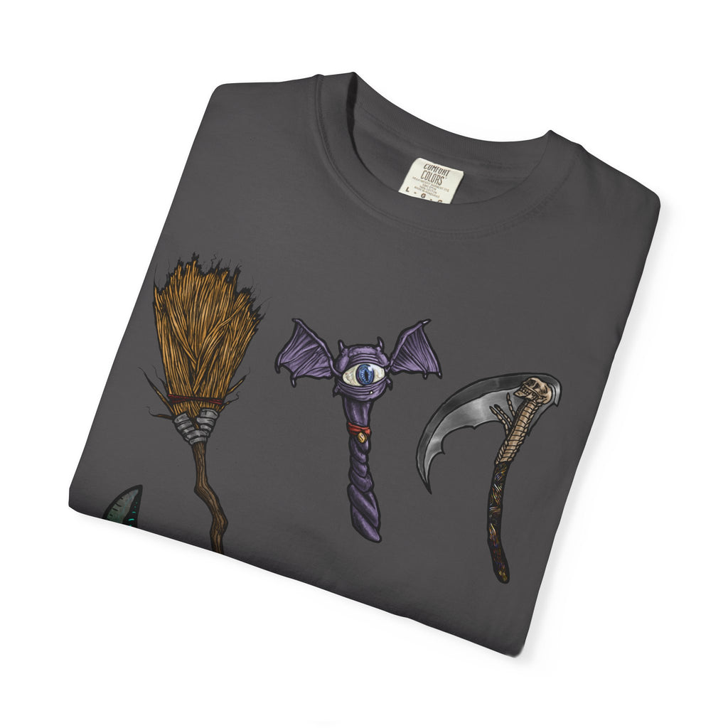 Hand-drawn Item Selection #1 t-shirt from Freaky Features showing a collection of monster weapons: broom, bat staff, skeletal scythe, shark dagger, ice cream cone and war hammer on dark gray tee
