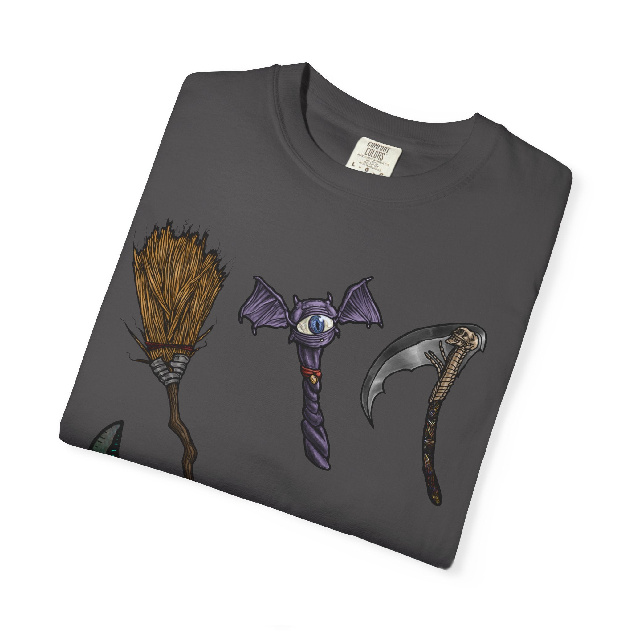 Hand-drawn Item Selection #1 t-shirt from Freaky Features showing a collection of monster weapons: broom, bat staff, skeletal scythe, shark dagger, ice cream cone and war hammer on dark gray tee
