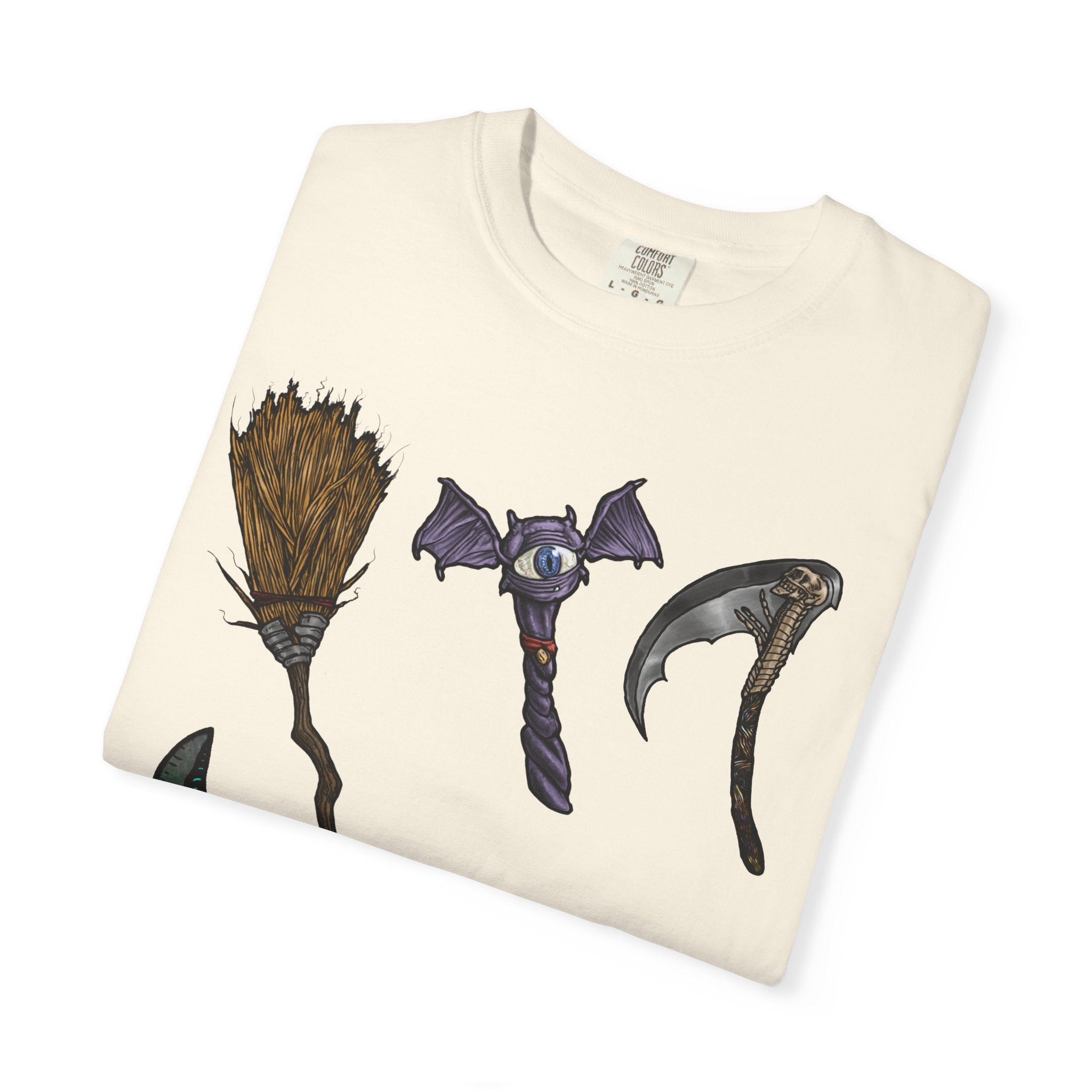 Hand-drawn Item Selection #1 t-shirt from Freaky Features showing a collection of monster weapons: broom, bat staff, skeletal scythe, shark dagger, ice cream cone and war hammer on dark gray tee
