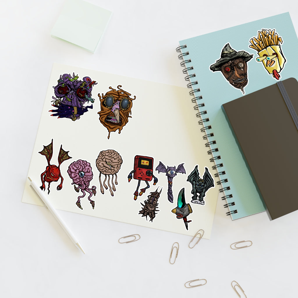 Freaky Features Sticker Sheet Set #3 , transparent die-cut sheet with 12 hand-drawn monsters and creatures including alien swarm, melting chocolate head, scarecrow, french fry box, walking Game Boy ( Gamerpal) , brains, and various weird weapons/creatures
